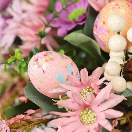 Details of the artificial wreath featuring a pink decorative egg and two small daisies